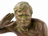 bronze statue of a man holding his head in his hands