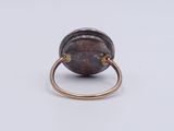 a close up of a ring on a white surface with a brown stone