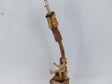 une sculpture en bois représentant une grue, posée sur un socle en bois, avec un fond blanc