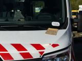 une camionnette blanche avec des bandes rouges et blanches garée dans un parking