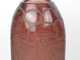 a red vase with a design on it sitting on a table