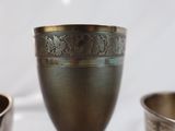 a silver cup sitting on a table next to other silver cups