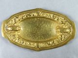 an old gold plate with a design on it sitting on a white surface