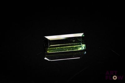 a green tourmaline gems on a black surface