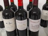 six bottles of red wine are lined up on a table