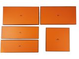 quatre boîtes orange sont empilées les unes sur les autres sur une surface blanche
