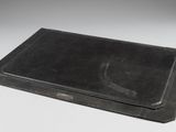an old black book with a black cover sitting on top of a white table