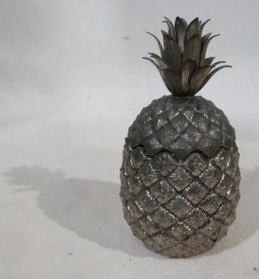 un ananas argenté posé sur une table blanche