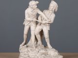 statue représentant un homme et une femme se tenant la main, posée sur une table en bois