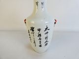 un vase blanc orné d'inscriptions asiatiques, posé sur une table