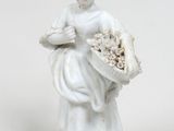 une statue blanche représentant une femme tenant un panier de fleurs