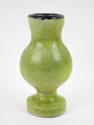 un vase vert posé sur une surface blanche