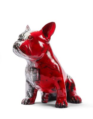 a red and black dog figurine sitting on a white surface