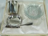 a silver cocktail shaker and a glass in a box