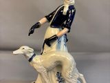 une figurine représentant une femme et un chien posée sur une table