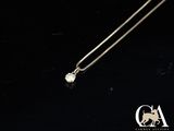 un collier en or blanc orné d'un diamant sur fond noir