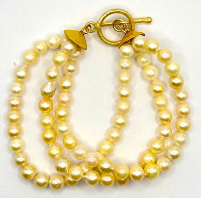 deux rangées de perles jaunes avec un fermoir en or sur fond blanc