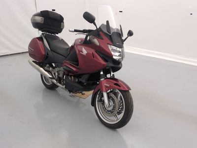 une moto rouge garée dans une pièce aux murs blancs