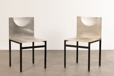 two chairs with a metal back and seat in a white room