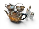 a group of silver teapots and glass bottles on a white surface