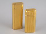 two gold lighters sitting next to each other on a white surface