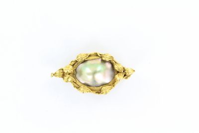 un gros plan d'une bague en or renfermant une perle