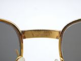 sunglasses with a gold frame and grey lenses on a white surface