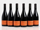six bottles of wine are lined up in a row on a white surface