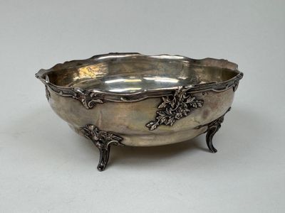 an antique silver bowl with grapes on it on a table