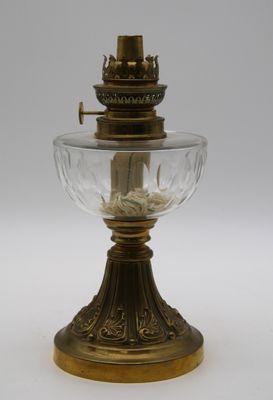 une lampe à huile ancienne en laiton et en verre sur fond blanc