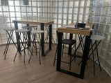des tables et des tabourets dans une pièce, avec un mur en briques de verre en arrière-plan