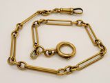 a close up of a gold chain with a ring on it