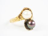 un gros plan d'une bague en perle et en or posée sur une surface blanche
