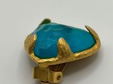 a close up of a gold and turquoise stone ring on a white surface