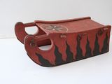 un petit traîneau en bois orné d'un motif rouge et noir