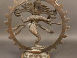 brass statue of a dancing person in the center of a circular frame