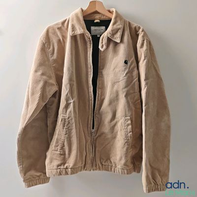 une veste beige suspendue à un mur à l'aide d'un cintre