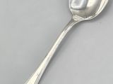 a silver spoon with a handle on a gray surface