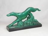 statue représentant un chien vert courant sur un rocher, sur fond blanc