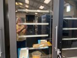 a woman standing in front of a glass door with food inside of it