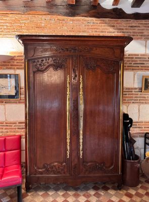 an image of a living room with a red chair and a wooden armoire