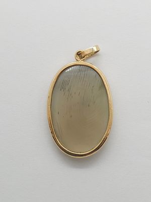 a close up of a yellow gold pendant with a white background