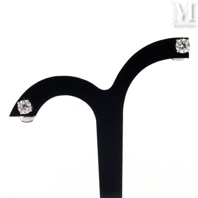a pair of earrings that are on a black stand