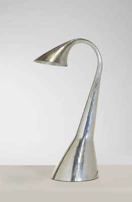 une lampe en métal argenté posée sur une table avec un fond blanc