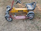 a small yellow tricycle that is sitting in the grass