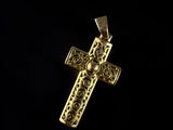 a gold cross pendant on a black background