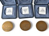 three gold medals are in a case and one has a medal on it