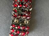 a close up of a bracelet with red and silver beads on it
