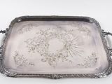 un plateau ancien en argent orné de motifs floraux sur fond blanc