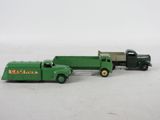 un petit camion vert et un autre petit camion vert posés sur une surface blanche